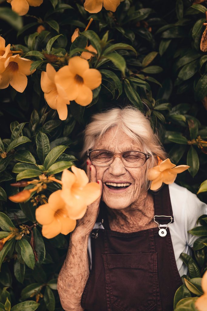 elderly woman smiling near flowers